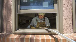 Image of a Renewal by Andersen employee installing a new window in a customer's home in Sacramento, CA